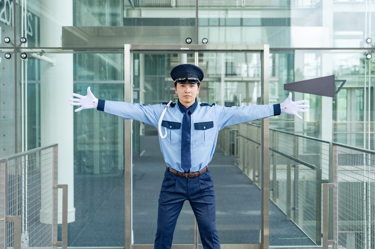 Un hombre con uniforme de policía bloquea la entrada a un edificio acristalado con los brazos en alto. Los atacantes de ransomware introducen un nuevo asesino EDR en su arsenal. Sophos descubre el uso de EDRKillShifter por los atacantes del ransomware RansomHub. Por Andreas Klopsch. Fuente de la imagen: Shutterstock